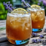 Vibrant lavender lemonade spritz in a glass with ice, garnished with lemon slice and fresh lavender sprigs, perfect for summer refreshment.