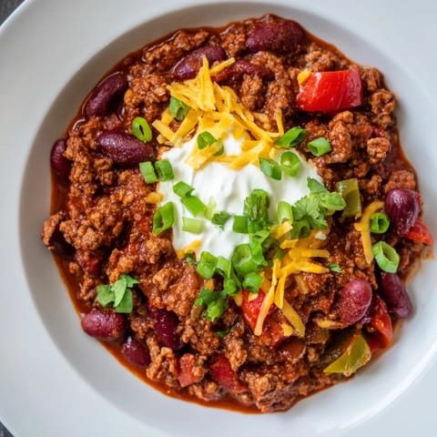 Hearty Chili con Carne garnished with sour cream and fresh cilantro, ready to be enjoyed.