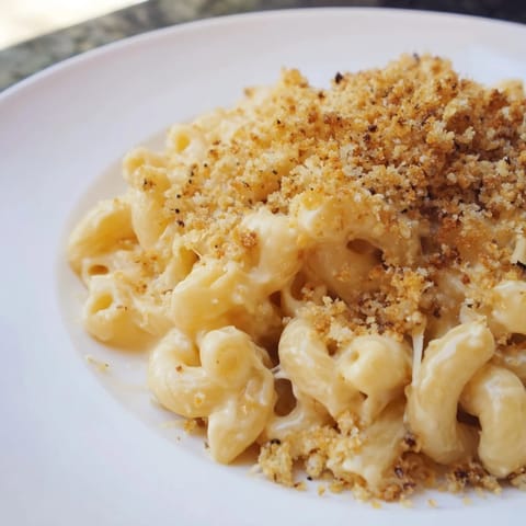 A close-up of creamy macaroni and cheese, boasting a crispy, toasted breadcrumb topping.