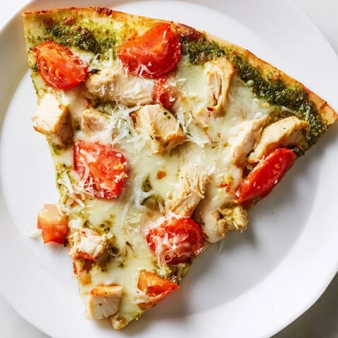 A close-up of golden-brown Chicken Pesto Pizza featuring basil pesto sauce and bubbling cheese, ready to serve for dinner.