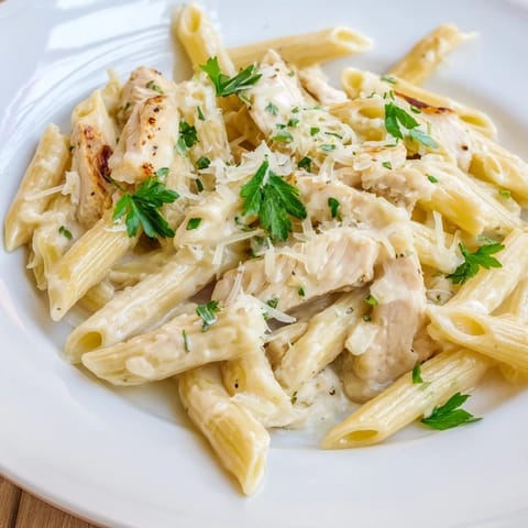 A hearty serving of Roasted Garlic Chicken Penne in a white bowl, showcasing tender chicken and al dente pasta.