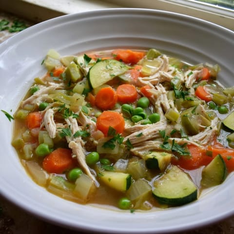 Spring Garden Chicken Soup simmering in a pot with vibrant zucchini and celery, ready to be ladled into rustic bowls.  