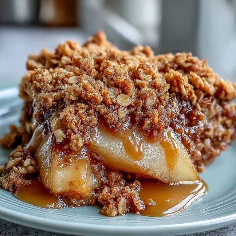 A serving of warm Pear Crumble with vanilla ice cream melting over the spiced fruit and crispy crumble topping.