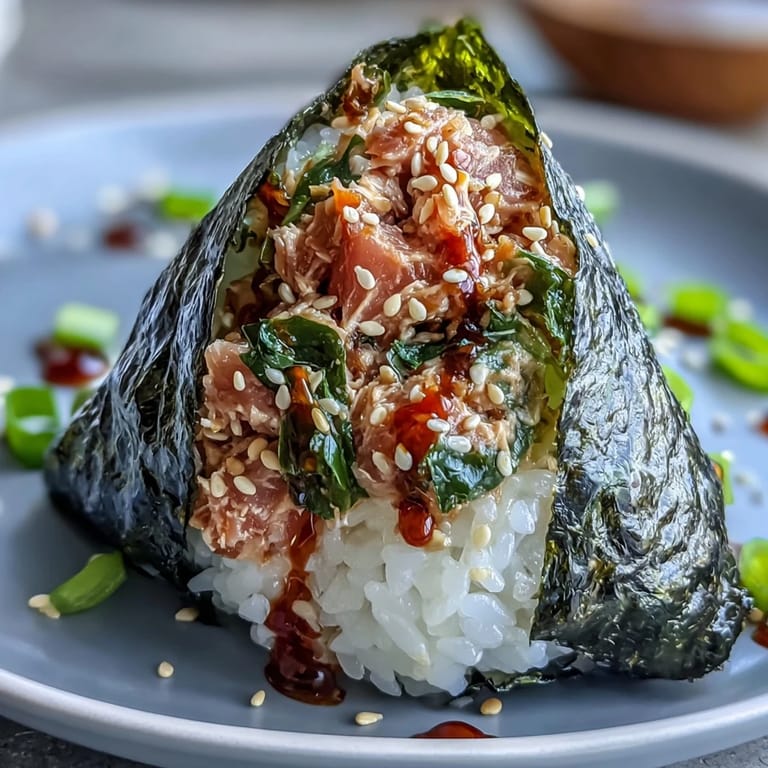 Handheld Japanese rice balls stuffed with spicy tuna mayo, wrapped in seaweed for a portable snack.  